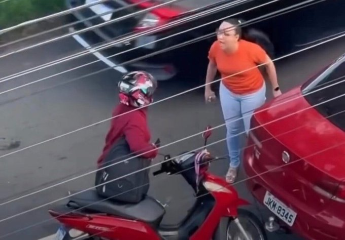 Uma colisão entre um Siena vermelho e uma Honda Biz terminou em discussão e agressão. 📹 Vídeo mostra o momento em que a motociclista dá um tapa no rosto da motorista após o acidente.